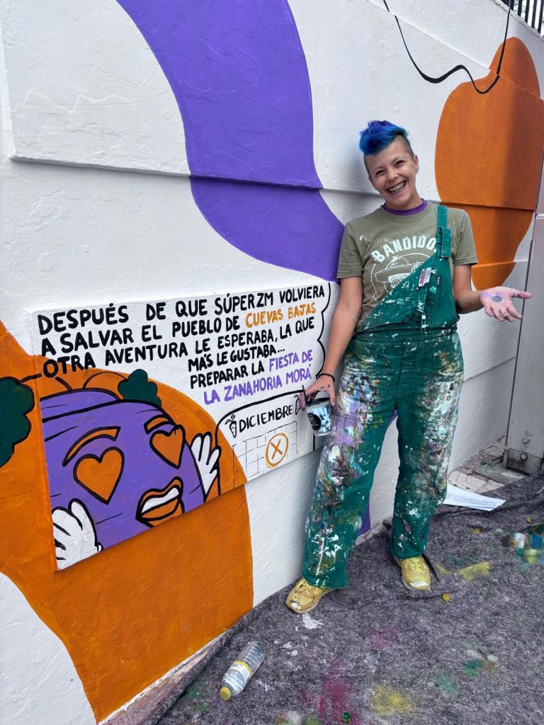 Daniela posa delante de su mural.