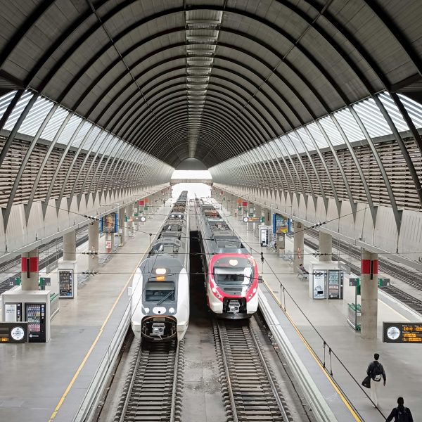 Vibrant scene at a modern train station in Seville, Spain, featuring sleek trains.