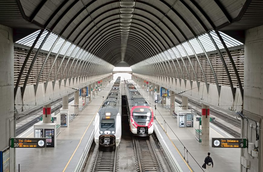 Vibrant scene at a modern train station in Seville, Spain, featuring sleek trains.