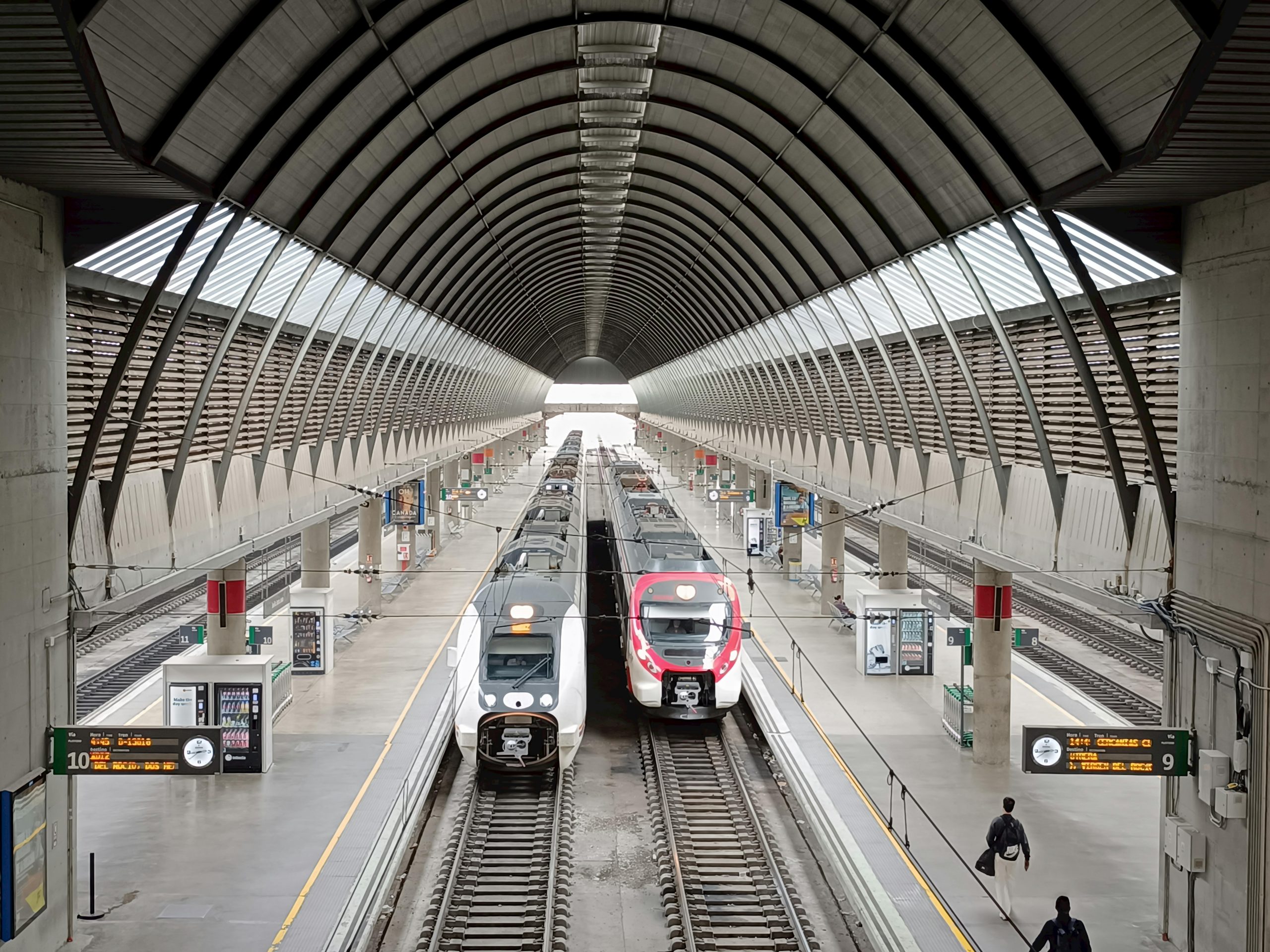 Vibrant scene at a modern train station in Seville, Spain, featuring sleek trains.