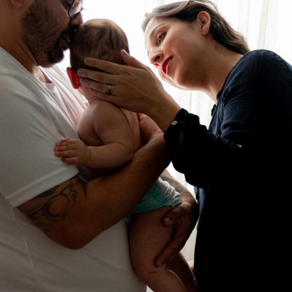 A tender family portrait capturing parents bonding with their baby indoors.