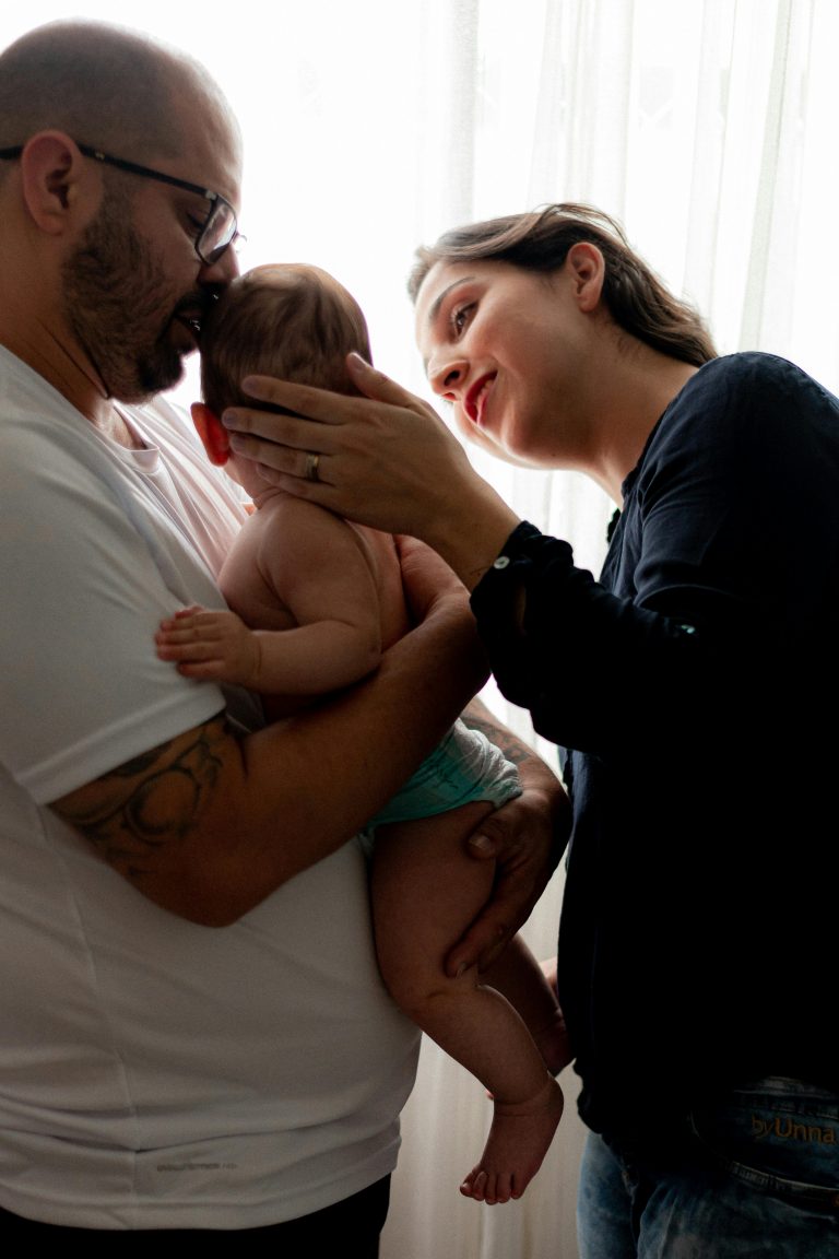 A tender family portrait capturing parents bonding with their baby indoors.