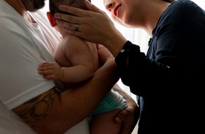 A tender family portrait capturing parents bonding with their baby indoors.